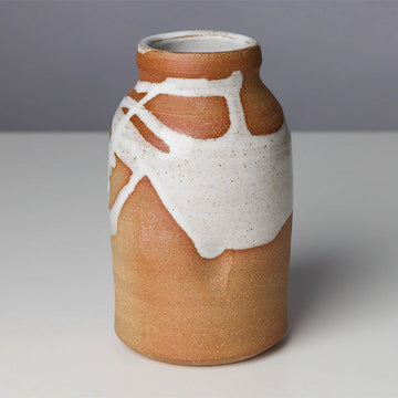A ceramic vase in a natural colour with white paint details splattered around the vase.