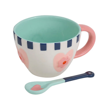 A ceramic mug with a matching spoon printed with hearts.