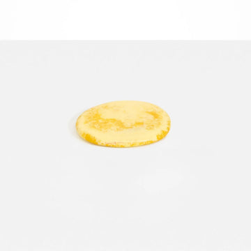An irregular shaped round coaster made from yellow resin.