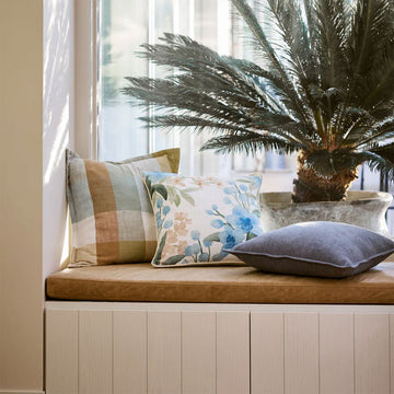 Checkered square cushion with a pattern of brown, beige, and white on a white background.