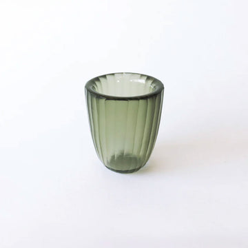 Green glass tumbler on a white background.