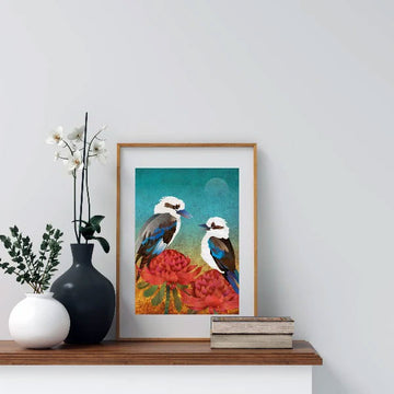 A framed print of an illustration of two kookaburras and two red waratah flowers.