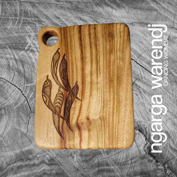A rectangle wooden board with a hole in the top corner and etched with a design of gum leaves.