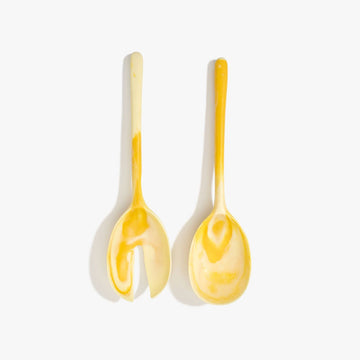 A pair of salad servers made from yellow resin.