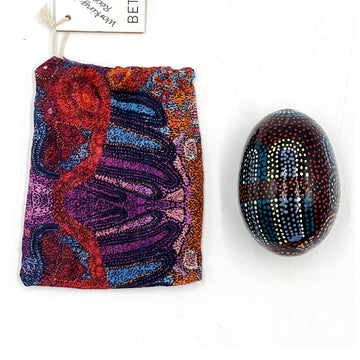 An ornamental egg printed with artwork by Andrea Adamson next to a matching fabric sleeve.