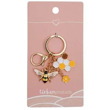 A keyring witha bee charm, honeycomb and flower attached to a pink card with the heading 'Urban Products'.