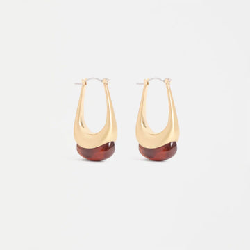 Gold hoop earrings with red accents on a white background.
