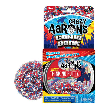 An open card packet titled 'Crazy Aarons Comic Book Super Powered Putty' with a round container inside. There is some putty next to the box with small red and blue pieces inside.