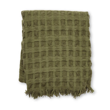A folded up throw in olive green with a waffle pattern.