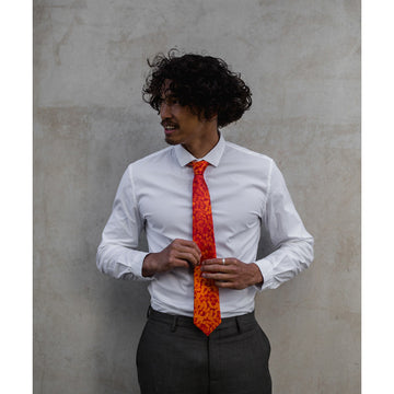 A tie in orange with lighter orange spots on top. Artwork by Muuki Taylor.
