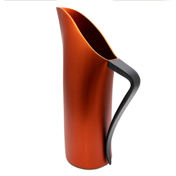 An orange red water jug with a black curved handle is standing on an angle.