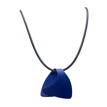 A pendant made from anodized blue stainless steel in the shape of a folded over wave on a black cord.