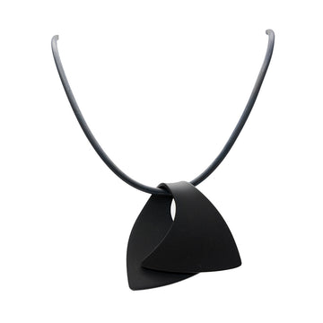 A pendant made from anodized black stainless steel in the shape of a folded over wave on a black cord.