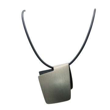 A pendant made from anodized black and charcoal stainless steel in the shape of a folded over square on a black cord.