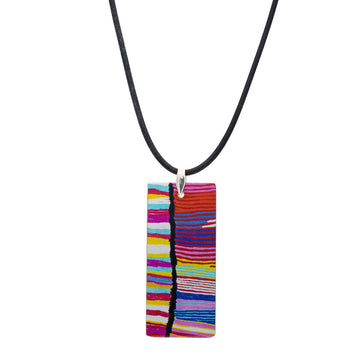 A rectangle pendant printed with artwork by Judy Watson on a black cord.