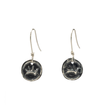 A pair of silver drop earrings with a footprint embossed on a circle.