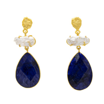 A pair of drop earrings with a gold top, white stone in the middle and a dark blue gemstone in the shape of a teardrop on the bottom.