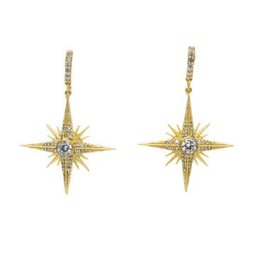A pair of earrings in gold with a four point star hanging below and covered with white diamonties.
