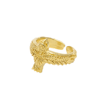 A gold plated ring in the shape of a falcon with its wings wrapping around the ring.