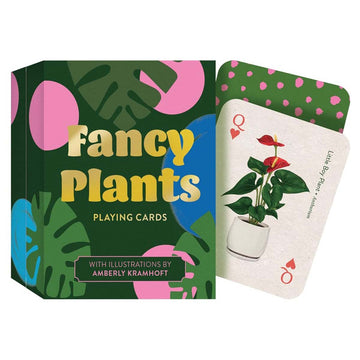 'Fancy Plants Playing Cards' green box pictured with illustrations of green leaves and pink and blue circles. A face up playing card is next to the box with an image of a red lily with leaves in a white pot. A green card with pink spots is face down behind it.