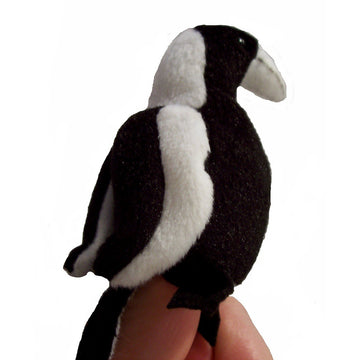 A plush magpie finger puppet sitting on a finger against a white background.