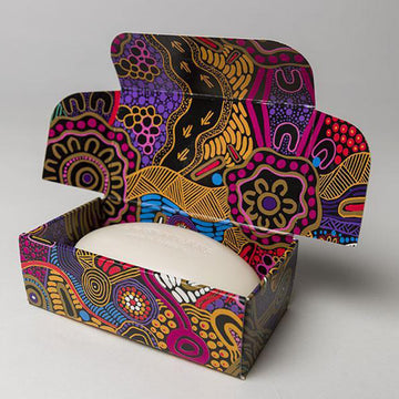 The gift box soap packaging featuring artwork by Justin Butler in gold, purple and pink. In the middle is a black box with the product details.