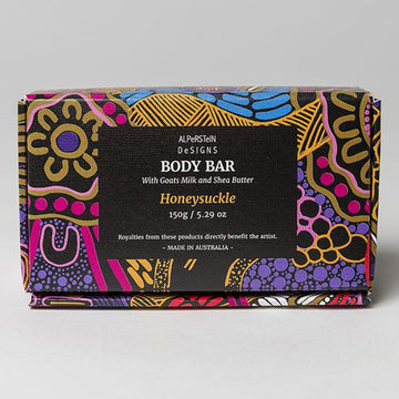 The gift box soap packaging featuring artwork by Justin Butler in gold, purple and pink. In the middle is a black box with the product details.