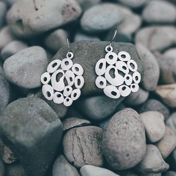 A pair of drop earrings in silver featuring a circular design made up of odd shaped circle outlines.