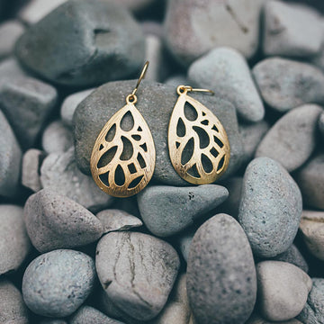 Teardrop shaped drop earrings in gold with a cut out design inside the teardrop.