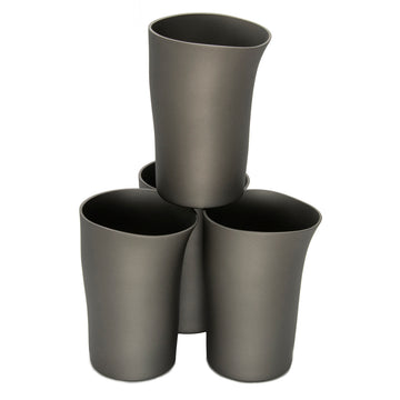 A set of four beakers in charcoal with a handcrafted shape are stacked up next to each other. One beaker is on top of the other three.