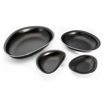 A set of four oval triangular shaped bowls in black laid out next to each other.