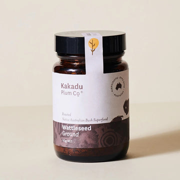 Amber coloured glass jar, black plastic lid, label with indigenous motif. Kakadu Plum Co, Australian Sustainable, wattleseed ground, type printed on label. Logo printed on tamper proof tab.Thick red smoothy served in in a chilled, handled jar, glass. Two purple and white cardboard straws, garnish on top. Smoothy is on a wooden bench, wattleseed packet at back.