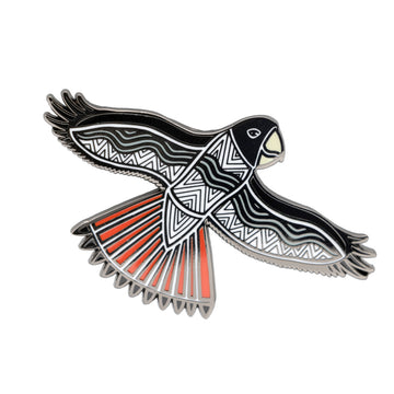 Enamel on metal brooch of a black and white patterned red tailed black cockatoo. The black cockatoo has black featured on the head and wings and is in flight position. 