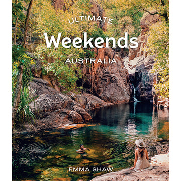 'Ultimate Weekends Australia' book cover features a man swimming in a lake and a woman sitting on a rock watching. They are surrounded by large rocks, trees and a small waterfall in the background.