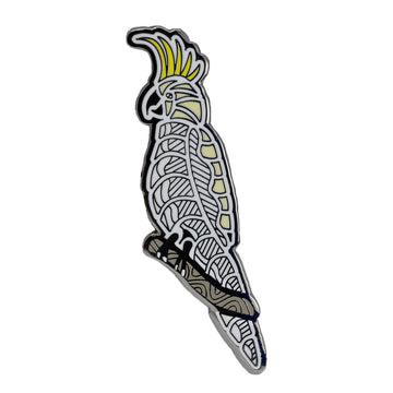 Enamel on metal black, white and yellow native Australian bird, the cockatoo. The cockatoo brooch is sitting on a branch with it’s yellow crest upright. 