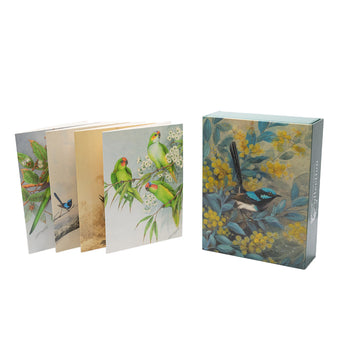 Four greeting cards are displayed overlapping each other on the left. The cards feature birds sitting in amongst leaves and flowers in a tree. On the right is a picture of the box which has an image of a blue and black bird sitting on a brand surrounded by yellow wattle.