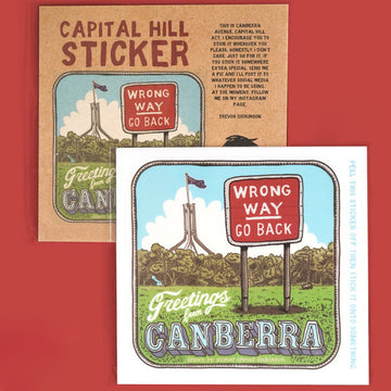 Sticker in the foreground of Parliament House, the sign Wrong Way Go Back and the heading Greetings from Canberra. In the background is the packaging.