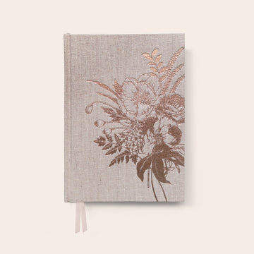 Front cover of a linen journal with a rose gold peony flower on the right.
