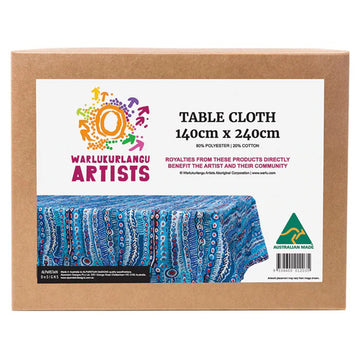 A brown box with a white label on the front with a photo of the blue table cloth inside with product information. The table cloth features artwork by Murdie Morris.