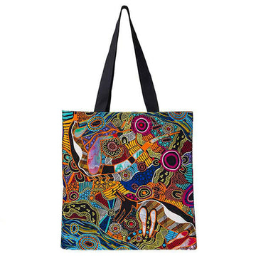 A tote bag with artwork printed on it by Justin Butler. The art contains the colours blue, orange and brown and the handles are black.