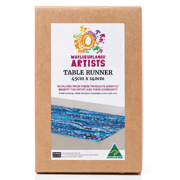 A brown box with a white product label on the front with a photo of the blue table runner inside. The table runner features artwork by Murdie Morris.