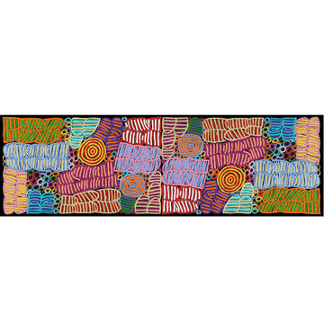 A silk scarf is folded up inside a dark grey box with a red border. There is a clear window on the front and the multicoloured scarf can be seen inside.