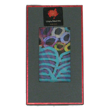 A silk scarf is folded up inside a dark grey box with a red border. There is a clear window on the front and the multicoloured scarf can be seen inside.