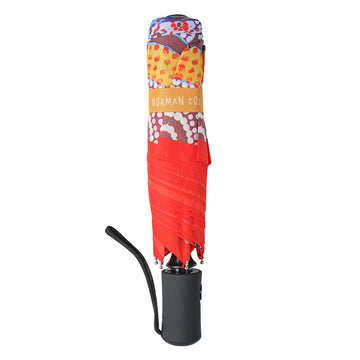 An open umbrella featuring artwork by Norman Cox in blue, red and orange.