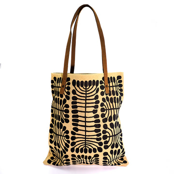 A tote bag in beige featuring a black print by Mitjili Napurrula on the front and brown handles.
