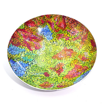 The inside of a salad bowl featuring artwork by Patricia Multa. The design features red, blue and green leaves.
