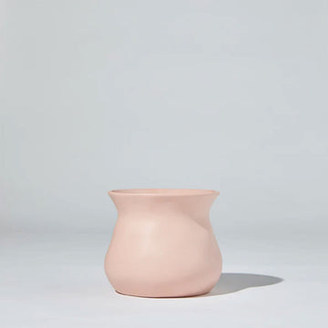 A short round vase with a curved top in pink ceramic against a grey background.