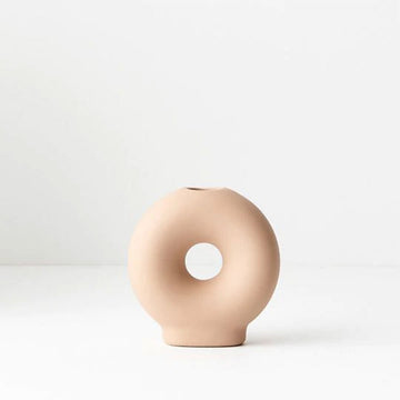 A round candle holder with a hole in the middle in nude ceramic.