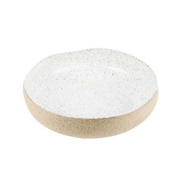 A round bowl with an imperfect shape made from stoneware and printed with a speckled pattern. The inside of the bowl is white and the outside is light brown.