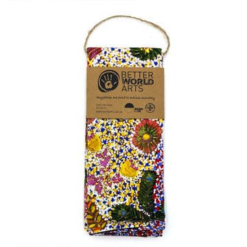 A printed tea towel featuring artwork by Julieanne Kngwarrey Morton of bush medicine plants in red, yellow, blue and green.